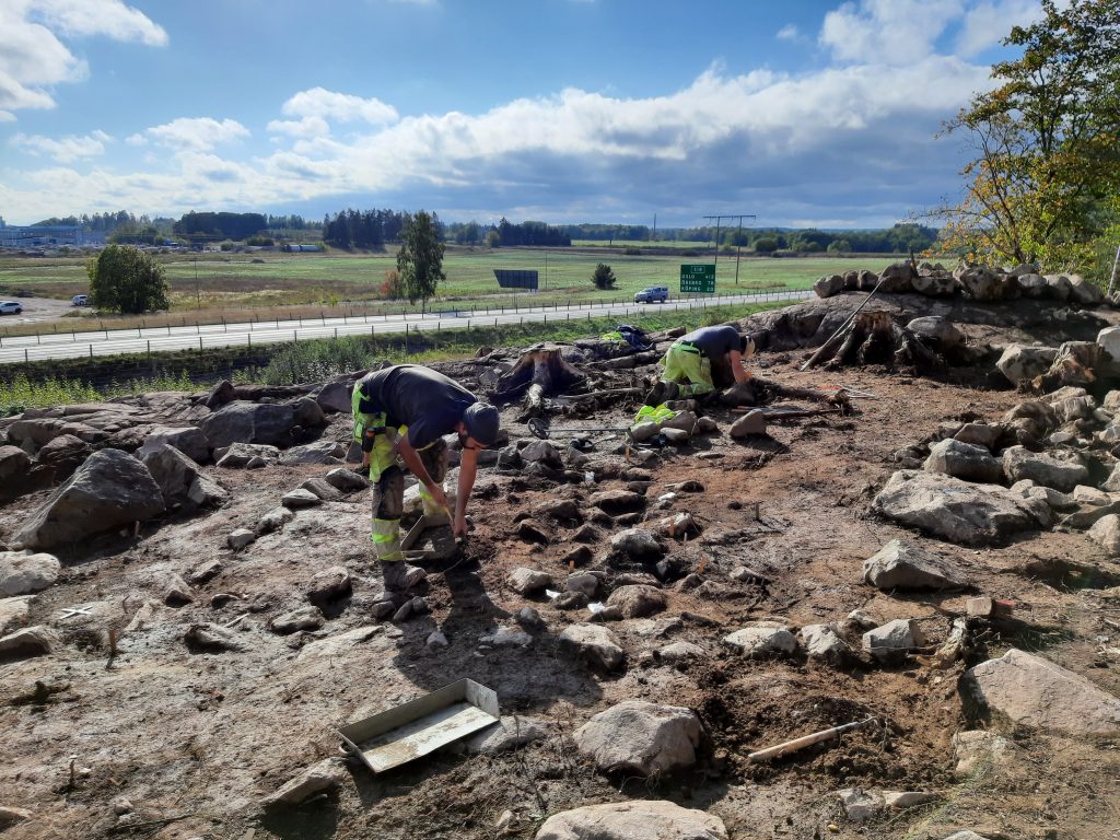Arkeologer rensar fram lämningar på en klippa.