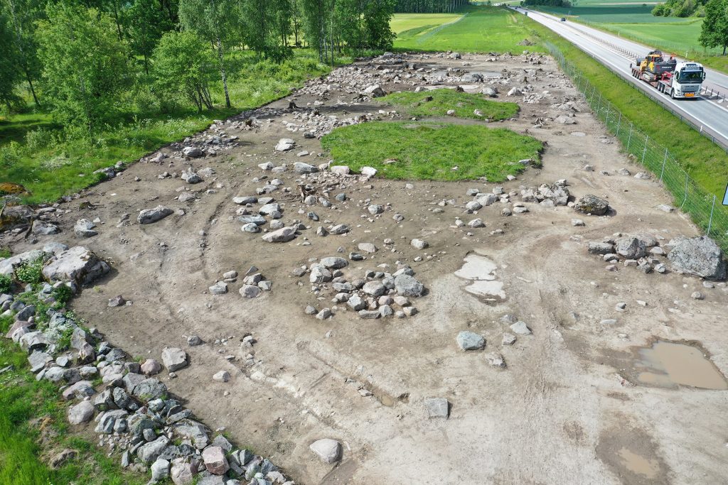 Översikt över Viby/Norrtuna från öster. Stolphuset som undersökts låg längst till vänster i bild. De två rundlarna av gräs är gravhögarna som undersökts under sommaren och hösten.