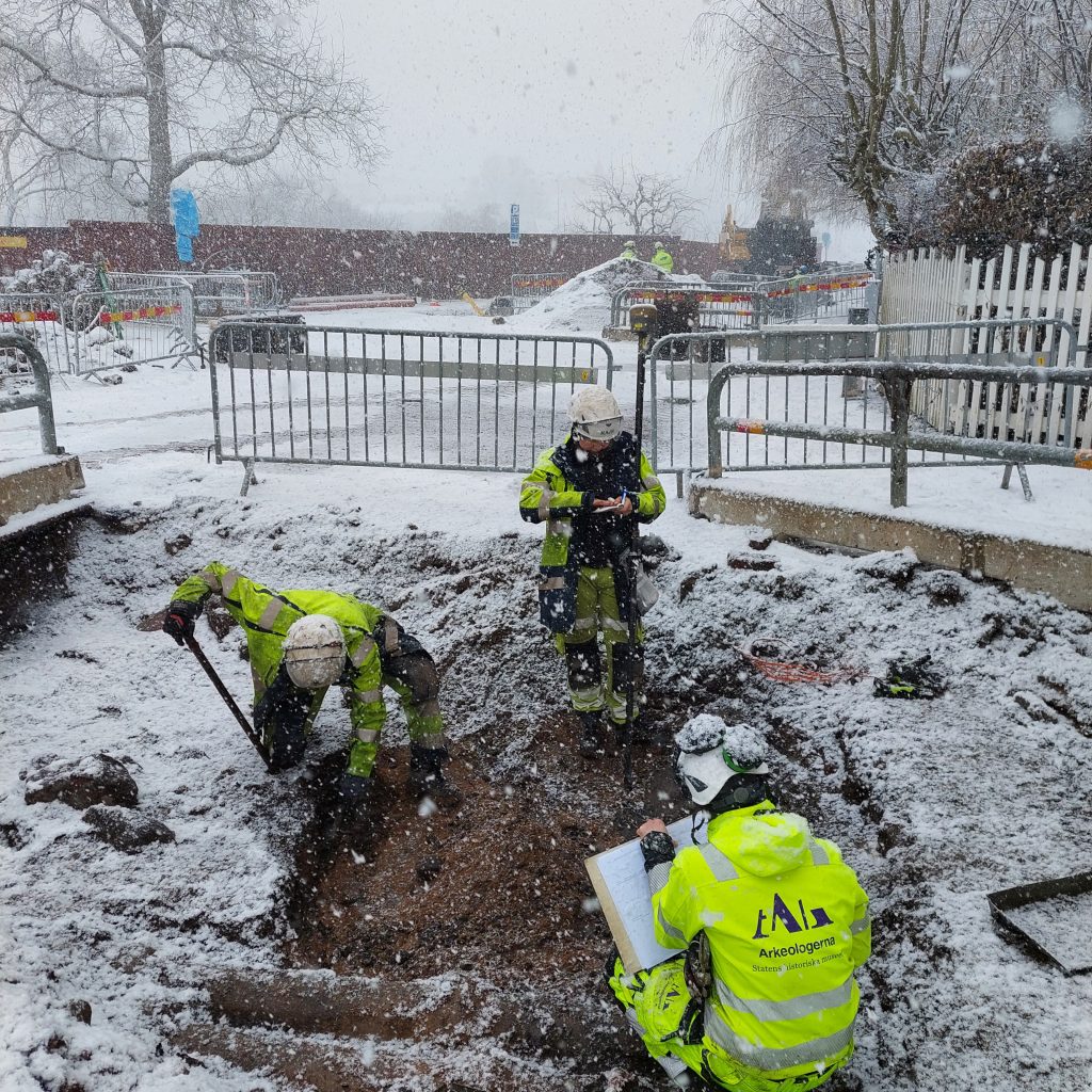 Arkeologer gräver i en gata. Snö runt omkring.