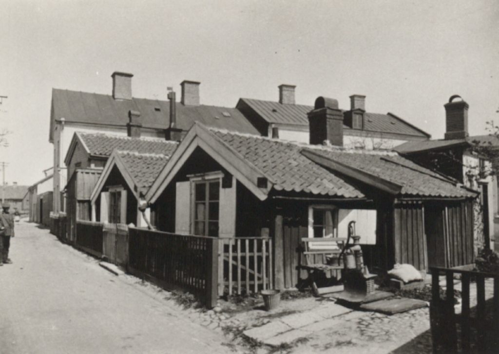 Gammal svartvit bild med trähusen. Från 1908.