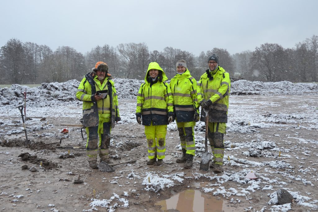 Fyra arkeologer ute på snöigt fält.