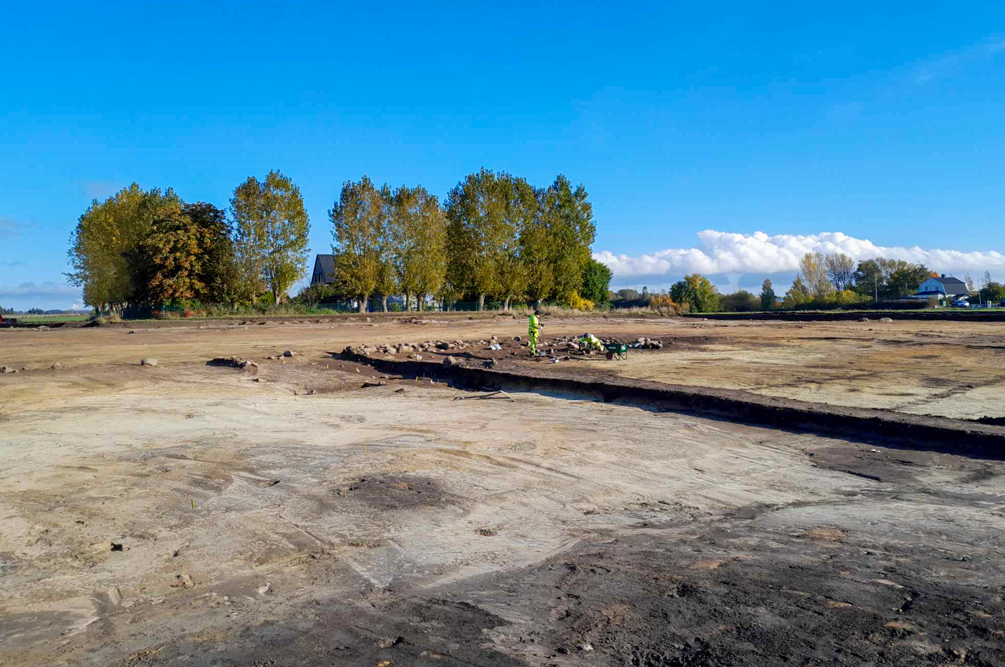 Stenkonstruktionen i den västra kanten av våtmarken med en profilbänk sparad. I förgrunden syns anläggningar i sterilen som ligger nedgrävda genom våtmarkslagret.