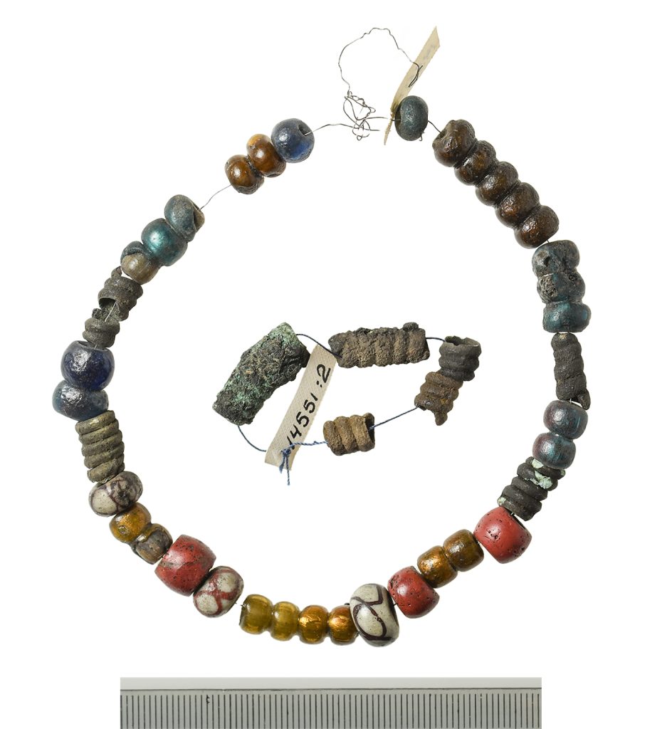 Pärlor i ett halsband och ett mindre band med pärlor mot vit bakgrund.