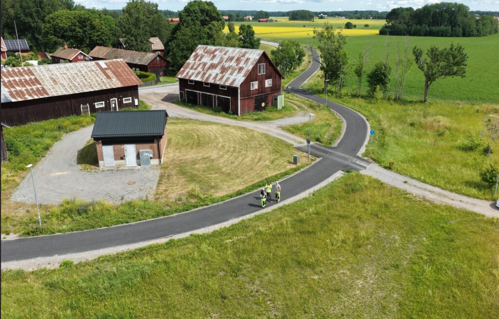 Ett öppet område med gräs med flera hus och en väg som går utanför.