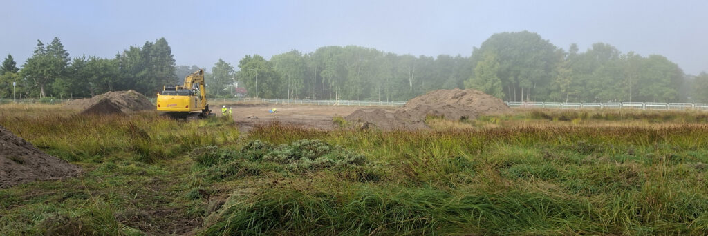 Ett öppet landskap med åker och skog i bakgrunden. Dimma över markerna.